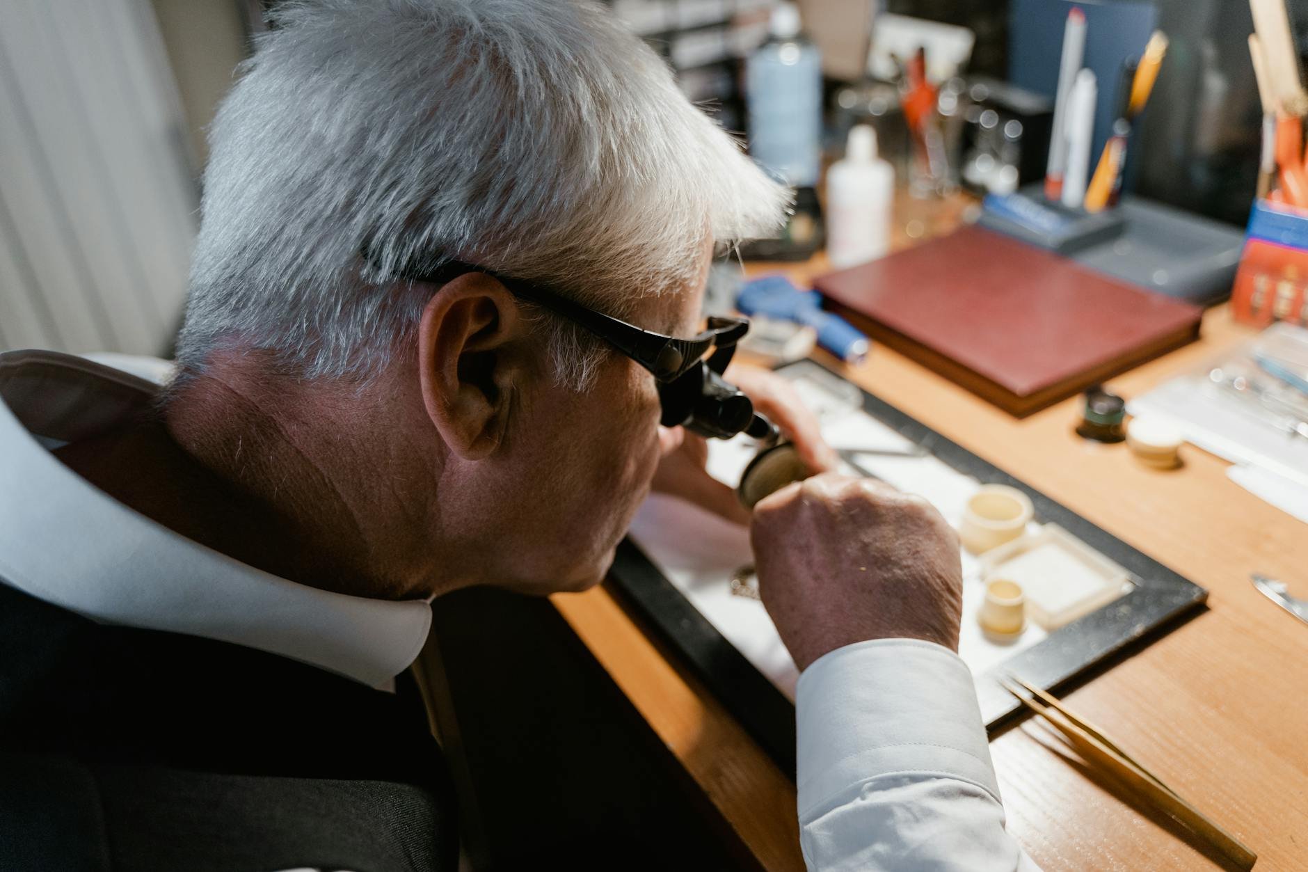 A professional watches247care technician using a jeweller's loupe to inspect the intricate details of a wristwatch