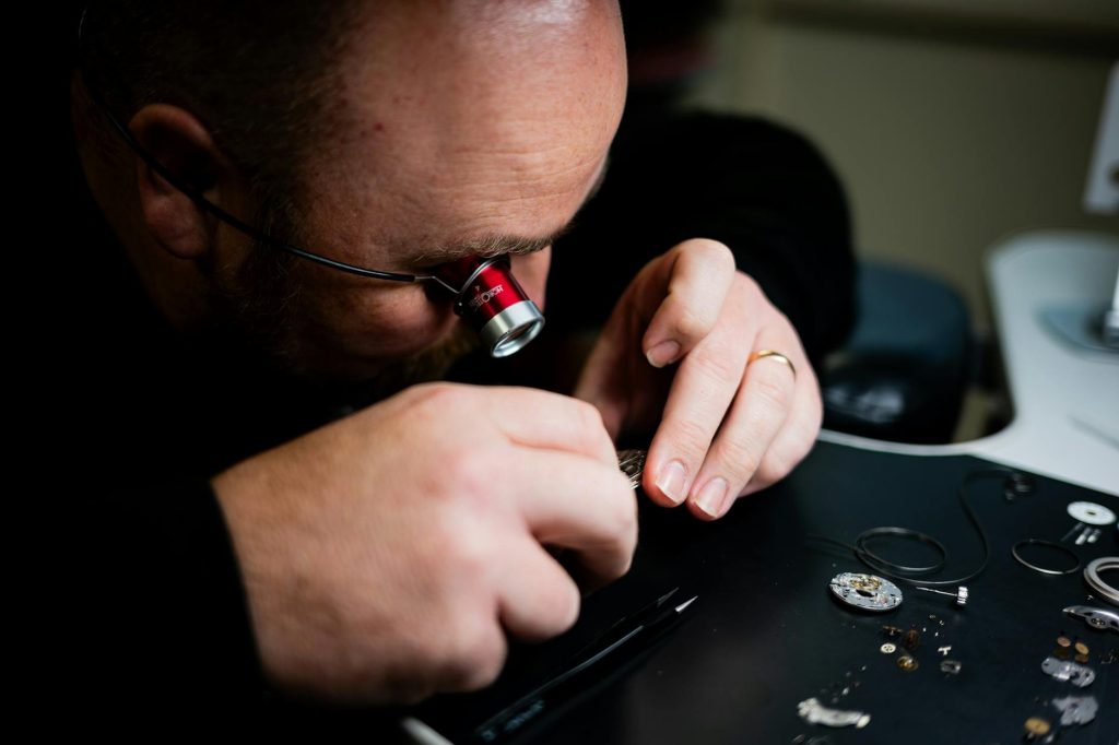 A skilled watchmaker carefully repairing a luxury timepiece on a professional workbench at watches247care in Kenya